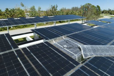 Park alanının gölgesinde, temiz enerjinin etkin üretimi için park etmiş arabaların güneş panellerine rüzgar hasarı.