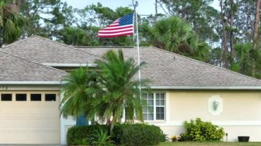 Florida özel evinin ön bahçesinde Amerikan bayrağı dalgalanıyor. Demokrasinin sembolü olarak gösterilen Amerikan yıldızlarının ve çizgilerinin havadan görünüşü.