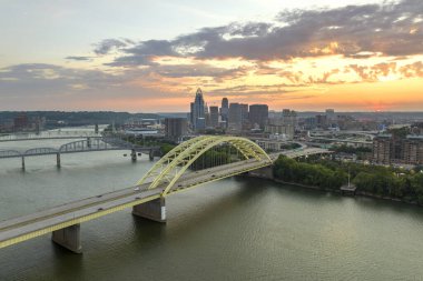 Ohio, ABD 'nin Cincinnati şehrinin şehir merkezindeki köprüde araç kullanan otoyol trafiği. Gün batımında ışıl ışıl parlayan yüksek ticari binalarla Amerikan şehri silueti.