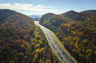 I-40 freeway in North Carolina leading to Asheville through Appalachian mountains in golden fall with fast moving trucks and cars. Interstate transportation concept.