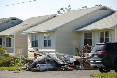 Kasırganın yol kenarındaki metal çöpler Florida yerleşim bölgesindeki evlere ağır hasar vermiş. Doğal afetten sonra.