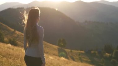 Yürüyüşçü kadın dağ yolunda dinleniyor. Doğa yürüyüşü sırasında el kaldırıyor ve akşam doğasının tadını çıkarıyor. Yüksek tepe yolundan geçen yalnız bir kadın gezgin. Sağlıklı yaşam tarzı kavramı.