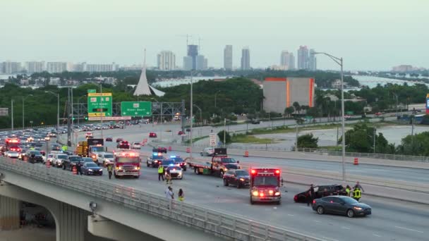 フロリダ州マイアミのアメリカンストリートの自動車事故現場に応答する最初の対応者と車両 米国の橋の道路で車両事故の犠牲者を支援する緊急サービス — ストック動画