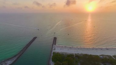 Venedik ve ABD 'nin Sarasota ilçesindeki Nokomis plajı yakınlarındaki renkli okyanus sularında limanda yol alan kaya iskelesi bariyerlerinin ve teknelerin günbatımı denizi..