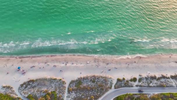 白い砂とアメリカのマナソータキーでリラックスした観光客との夜のブラインドパスビーチの上からの眺め メカ湾の水で泳ぎ 暖かいフロリダの太陽の下で休む休暇時間を楽しんでいる人々 — ストック動画