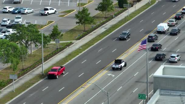 从空中俯瞰着宽阔的多车道公路 汽车在行驶 美国国旗在飘扬 美国的城市交通 美国城市从高处的交通 — 图库视频影像