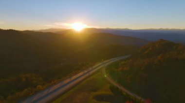I-40 freeway road leading to Asheville in North Carolina thru Appalachian mountains with yellow fall forest and fast moving trucks and cars. Concept of high speed interstate transportation.