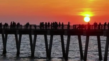 İnsanlar Florida 'daki Venice balıkçı iskelesinde gün batımının keyfini çıkarıyorlar. Deniz kenarında temiz hava alan yaz aktiviteleri.