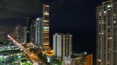 Yoğun trafik ve yüksek gökdelen binaları ile aydınlık şehir caddesinin yukarıdan görüntüsü Florida, ABD 'de Sunny Isles Beach şehir merkezinde. Gece vakti Amerikan turist bölgesi.