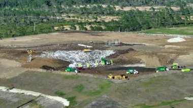 Yerin altına büyük miktarda çöp gömen buldozer traktörleriyle dolu büyük atık sahasının havadan görünüşü. Modern tüketiciliğin çevre üzerindeki zararlı etkisi.