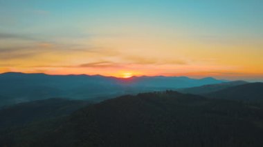 Parlak sisli sabahın hava manzarası sonbahar gündoğumunda dağlık orman ağaçlarıyla birlikte karanlık tepelerin üzerinde. Şafak vakti vahşi ormanın güzel manzarası.