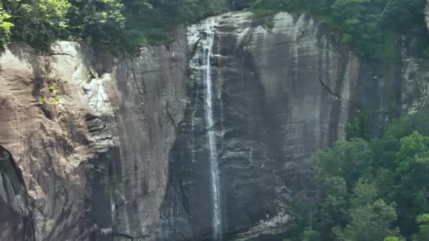 美国北卡罗来纳州Chimney Rock州立公园绿树成荫的森林之间 山核桃源瀑布从岩石巨石上落下来的清澈的水 — 图库视频影像