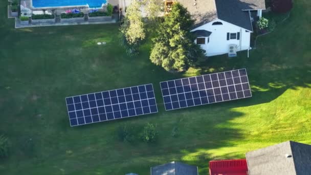 郊外の農村部できれいな生態系の電気エネルギーを発生させるために裏庭の地面に独立したフレーム上に太陽光発電パネルを搭載した民家 自律住宅の概念 — ストック動画