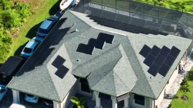 Kenar mahallelerde temiz ekolojik elektrik enerjisi üretmek için çatısı güneş fotovoltaik panellerle kaplı standart bir Amerikan yerleşim evi. Özerk konut kavramı.