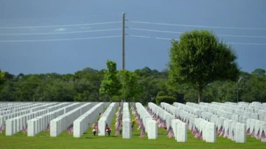 Yeşil çimlerin üzerinde beyaz mezar taşları olan Amerikan ulusal mezarlığı. Anma Günü konsepti