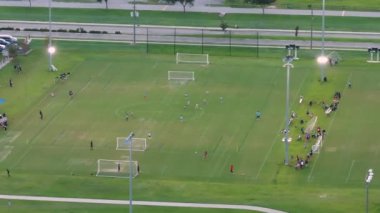 Okul çocukları gün batımında okul stadyumunda fiziksel egzersiz yaparken futbol oynuyorlar. Aktif yaşam konsepti.