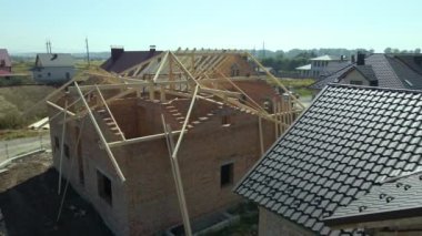 Aerial view of unfinished residential house with wooden roof frame structure under construction.