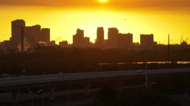 Yolcu uçağı gün batımında ABD 'nin Florida kentindeki Tampa şehrinin şehir merkezindeki yüksek gökdelen binalarından kalkacak. Ticari finans bölgesiyle Amerikan megapolis.