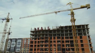 Tower cranes and frame structure of high residential apartment buildings at construction site. Real estate development.