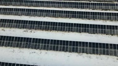 Aerial view of snow melting from covered solar photovoltaic panels at sustainable electric power plant for producing clean electrical energy. Low effectivity of renewable electricity in winter.