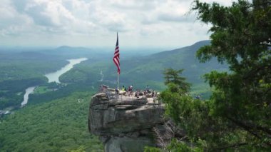 Amerikan ulusal bayrağını öven Chimney Rock ve Kuzey Carolina 'daki Chimney Rock State Park' ta bir sürü turist. Appalachian dağlarında gidilecek yer.