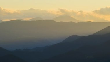 Tepenin yamacındaki eski köylü evleri. İnanılmaz bir dağ manzarası. Vahşi ulusal park dağlarında koyu ladin ormanlarıyla renklendirilmiş günbatımı.
