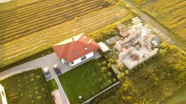 Biri ahşap çatı iskeleti ve diğeri de kırmızı kiremit çatılı iki özel evin yukarıdan aşağıya bakan görüntüsü..