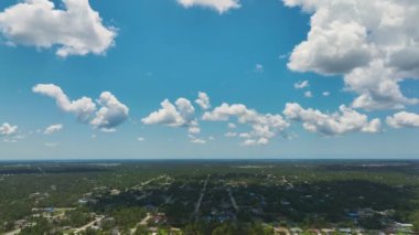 Florida 'nın sakin kırsal kesimindeki banliyö özel evlerinin hava manzarası. Banliyölerin üzerinde beyaz bulutlu mavi gökyüzü.