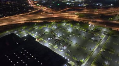 Aerial night view of many cars parked on parking lot with lines and markings for parking places and directions. Place for vehicles in front of a grocery mall store.