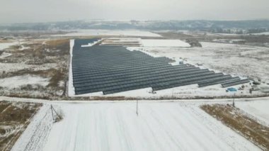 Aerial view of electrical power plant with solar panels covered with snow melting down in winter end for producing clean energy. Concept of low effectivity of renewable electricity in northern region.