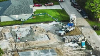 Yeni ev inşaatındaki işçilerin havadan görünüşü duvarlar ve çatı için beton döşeme temelleri döşemeye hazır..