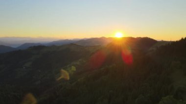 Parlak batan güneşle aydınlanan karanlık çam ormanı. Vahşi dağlarda renkli günbatımının havadan görünüşü. Güzel doğa manzarası.