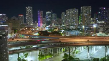Miami, Florida 'da geceleri otoyol kavşağının yukarısında, hızlı sürüş araçları olan modern Amerikan şehri. ABD kentsel altyapısının hava görüntüsü.