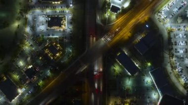 Gece vakti Amerikan şehrinde trafik ışıkları ve hareket halindeki arabaların kesiştiği büyük çok şeritli kavşağın üst görüntüsü. ABD 'de ulaşım sisteminin zaman aşımı.