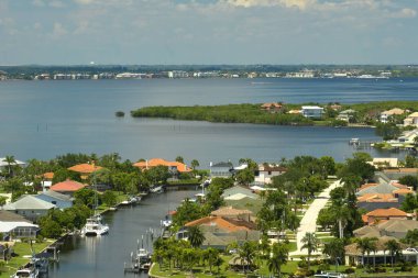 Florida yakınlarındaki deniz kıyısındaki uzak banliyölerdeki kırsal özel evlerin havadan görüntüsü körfez kıyısında yeşil bitki örtüsü olan sulak alanlar. Tropikal bölge kavramında doğaya yakın yaşamak.