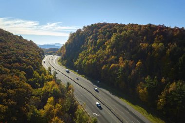 I-40 freeway road leading to Asheville in North Carolina thru Appalachian mountains with yellow fall forest and fast moving trucks and cars. Concept of high speed interstate transportation.