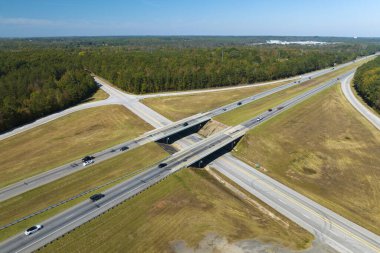 View from above of busy american highway with fast moving traffic between woods. Interstate transportation concept.