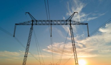 Gün batımında elektrik hatları olan yüksek voltaj kulesi. Elektrik aktarımı.