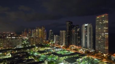 Florida, ABD 'deki Sunny Isles Beach şehrinin şehir merkezindeki gece şehir manzarası. Modern Amerikan megapolis 'indeki parlak gökdelen binalarıyla gökdelenler..