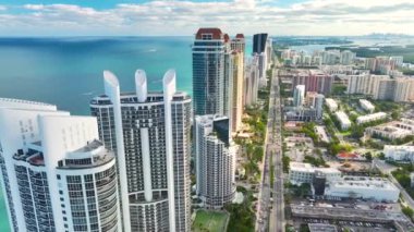Sunny Isles Beach City 'deki Atlantik Okyanusu kıyısındaki lüks otellerin ve apartmanların manzarası. Kalabalık trafiği olan bir şehir caddesi. Güney Florida 'daki Amerikan turizm altyapısı.