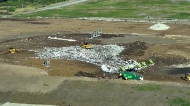 Yerin altına büyük miktarda çöp gömen buldozer traktörleriyle dolu bir çöp sahası. Açık atık yönetiminin çevre üzerindeki zararlı etkisi.