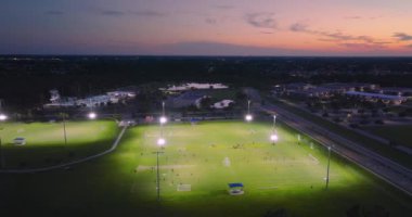 Gün batımında çimen stadyumunda futbol maçına katılan insanların olduğu parkın havadan görüntüsü. Aktif yaşam konsepti.