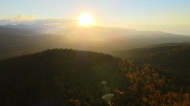 Gün batımında puslu tepeleri ve sisli vadisi olan güzel panoramik dağ manzarası.