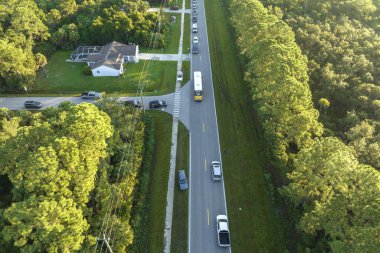 Sabahın erken saatlerinde Amerikan sarı okul otobüsünün kaldırımdaki otobüs durağından çocukları aldığı hava görüntüsü. ABD 'de toplu taşıma.