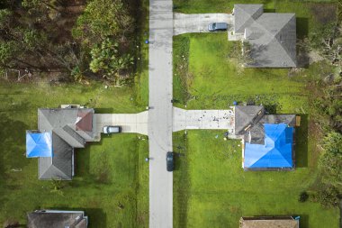 Asfalt kiremitlerin yerine konana kadar yağmur suyu sızıntılarına karşı koruyucu branda örtüleriyle kaplı çatı sızdıran evin üst görüntüsü. Florida 'daki Ian Kasırgası' nın yol açtığı çatı hasarı.