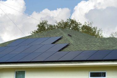 Kenar mahallelerde temiz ekolojik elektrik enerjisi üretmek için çatısı güneş fotovoltaik panellerle kaplı standart bir Amerikan yerleşim evi. Özerk konut kavramı.