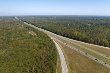 View from above of busy american highway with fast moving traffic between woods. Interstate transportation concept.