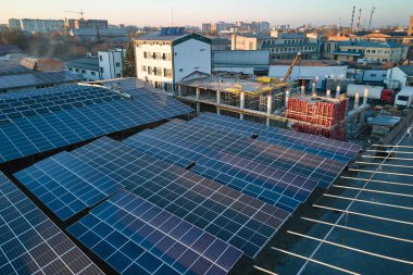 Sanayi binasının çatısına yeşil ekolojik elektrik üretmek için monte edilmiş mavi fotovoltaik panelli güneş enerjisi santralinin hava görüntüsü. Sürdürülebilir enerji konsepti üretimi.