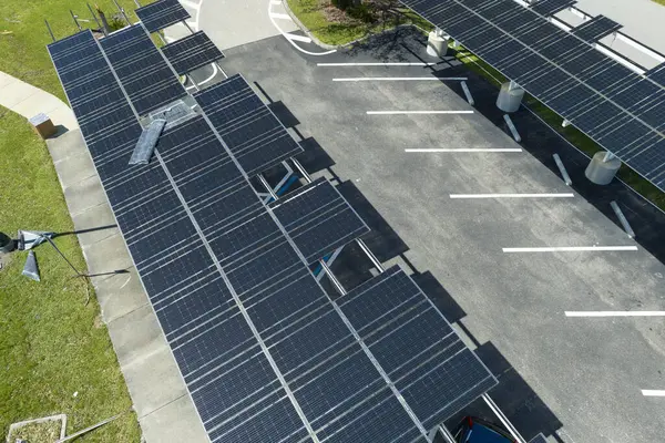 Destroyed by hurricane wind photovoltaic solar panels mounted on carport roof for producing green ecological electricity for electric vehicle charging. Consequences of natural disaster in Florida.