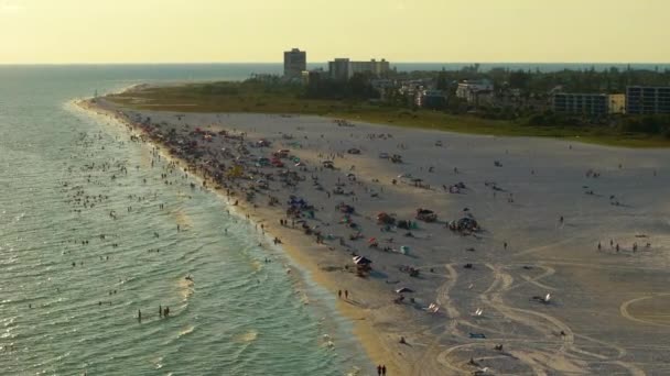 米国サラソータ州のシエスタキーサンディビーチとの空中夕方の海岸 暖かいメキシコ湾の水で泳ぎ フロリダの暑い日差しで日光浴を楽しむ多くの観光客 — ストック動画